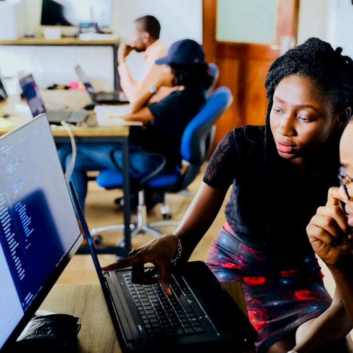Developers working through code on a laptop in a training lab